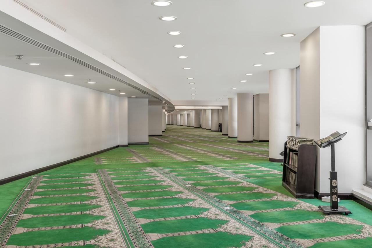 Hotel Jabal Omar Hyatt Regency Makkah La La Mecca Esterno foto The photo shows a spacious, well-lit indoor area with a green carpet designed for prayer. The carpet features a decorative pattern and outlines spaces where individuals would pray. There are white walls and several light fixtures in the ceiling provi
