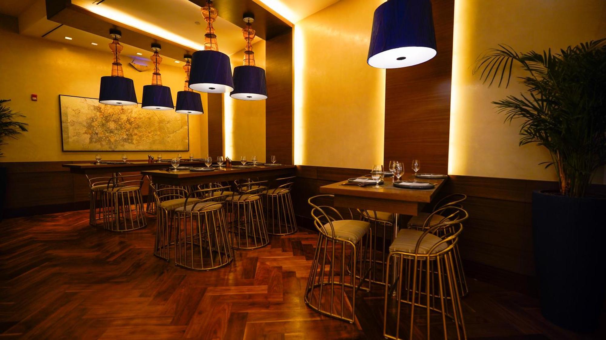 Hotel Jabal Omar Hyatt Regency Makkah La La Mecca Esterno foto The photo shows an elegantly designed restaurant interior. It features stylish seating arrangements with gold wire chairs paired with tables. The ambient lighting is warm, with a mix of recessed lights and pendant lamps that have blue shades, creatin
