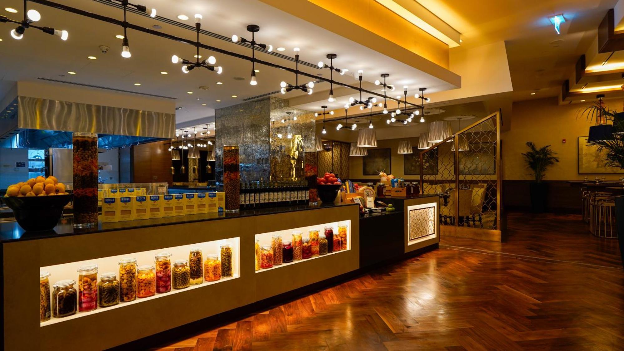Hotel Jabal Omar Hyatt Regency Makkah La La Mecca Esterno foto The photo shows a stylish interior of a restaurant or café. It features a well-lit space with modern lighting fixtures hanging from the ceiling. The focal point is a counter area with jars filled with colorful ingredients or snacks, illuminated by li