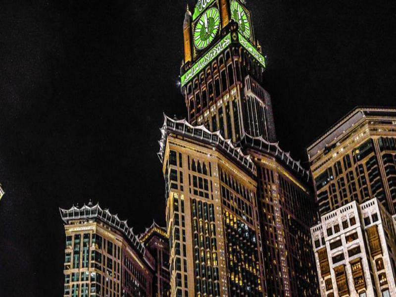 Hotel Jabal Omar Hyatt Regency Makkah La La Mecca Esterno foto The photo shows a tall building, which is a prominent feature of a city skyline, illuminated against a dark night sky. At the top of the building is a large clock tower, noticeable for its distinct green color, and intricate architectural details. Th