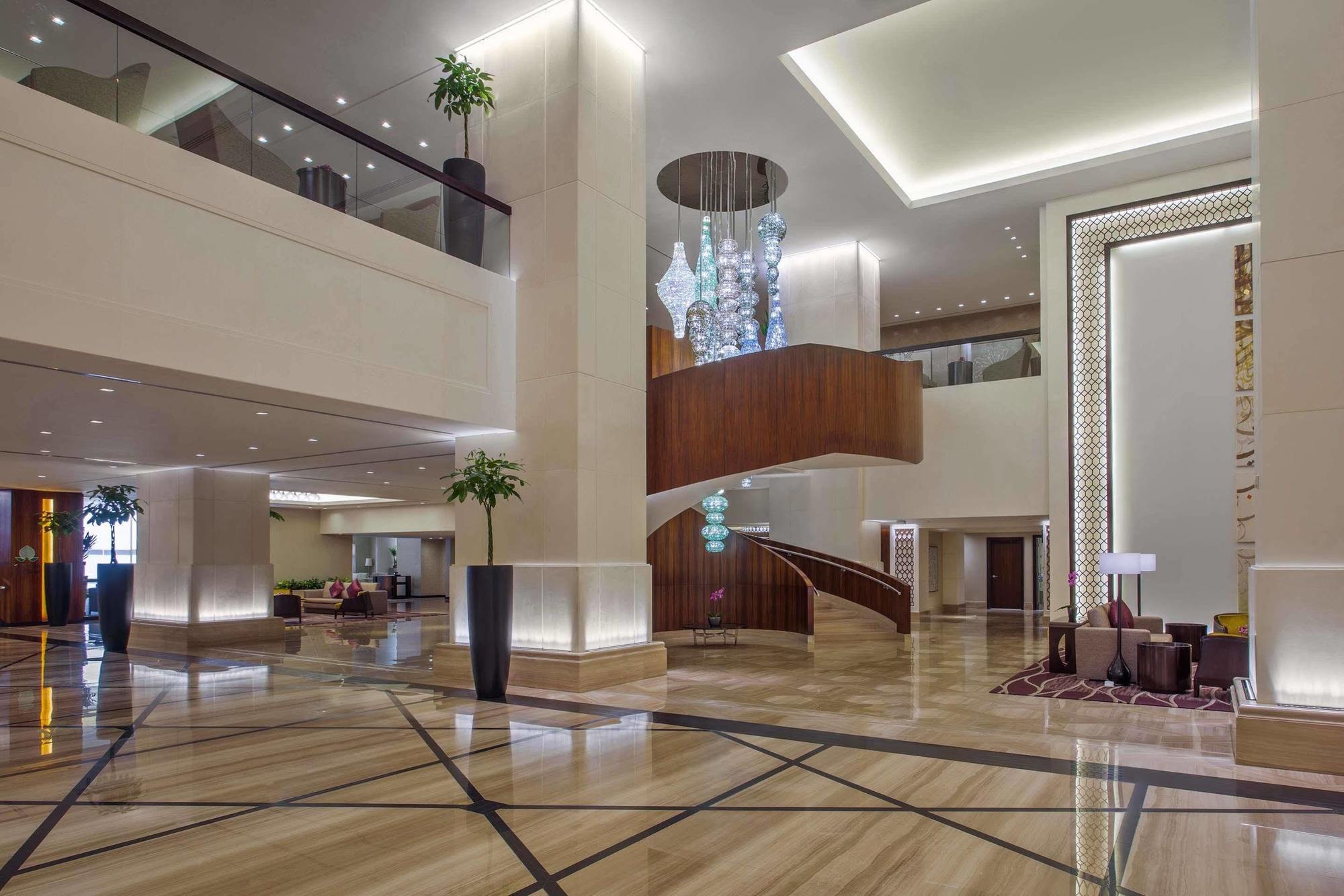 Hotel Jabal Omar Hyatt Regency Makkah La La Mecca Esterno foto The photo shows a spacious and elegantly designed hotel lobby. The interior features large marble flooring with a geometric pattern, complemented by modern lighting fixtures. A grand staircase with wooden accents is prominent in the center, leading t