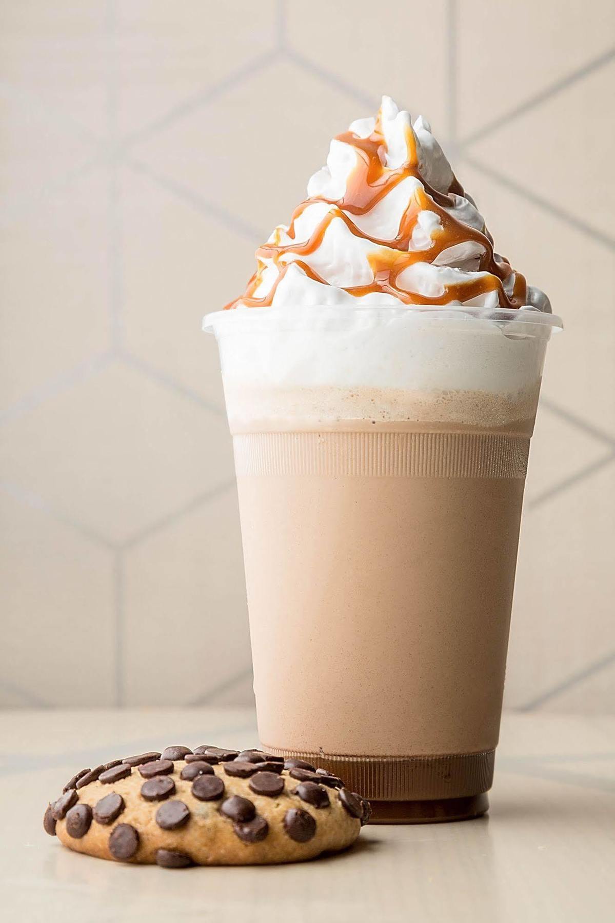 Hotel Jabal Omar Hyatt Regency Makkah La La Mecca Esterno foto The photo shows a tall cup of a creamy beverage, likely a milkshake or a blended coffee drink. The drink has a light brown color with a frothy top, which is topped with whipped cream. Drizzled over the whipped cream is a thick caramel sauce, adding a