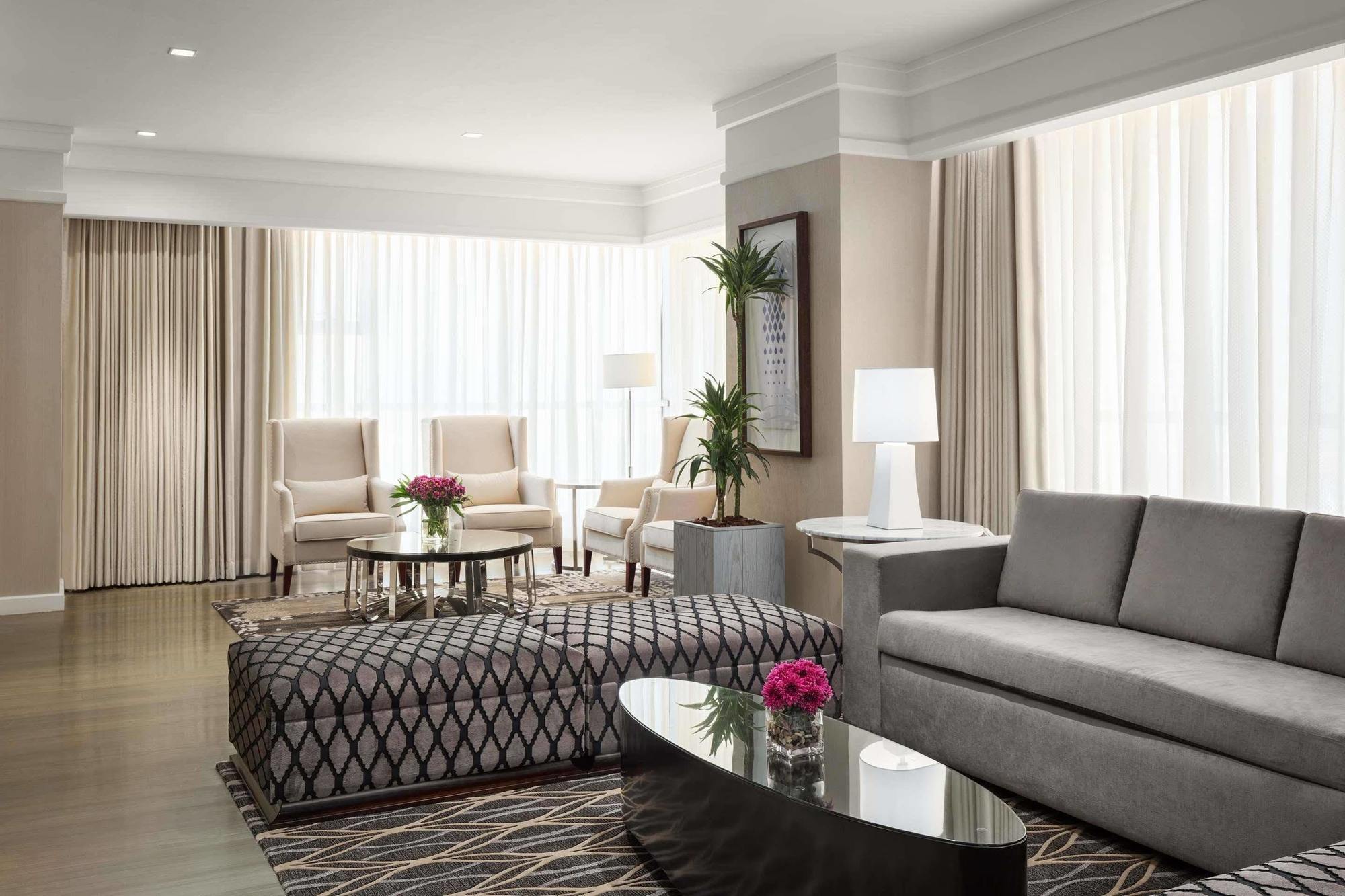Hotel Jabal Omar Hyatt Regency Makkah La La Mecca Esterno foto The photo depicts a modern living room with a stylish and inviting design. There are large windows covered with light-colored curtains that allow natural light to fill the space. The furniture includes a gray sofa, a patterned ottoman with a geometri