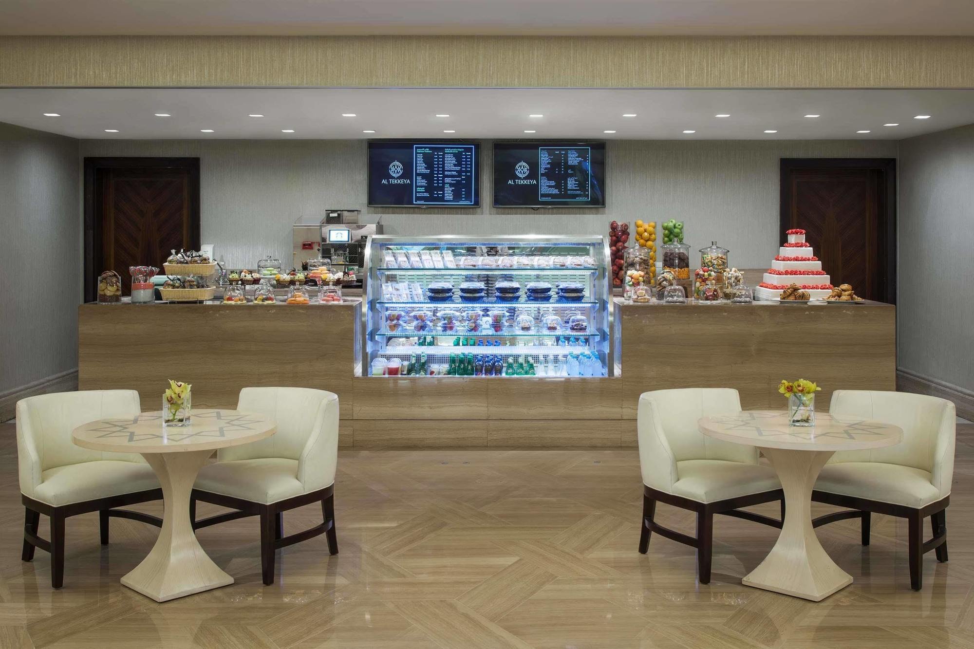 Hotel Jabal Omar Hyatt Regency Makkah La La Mecca Esterno foto The photo shows a quaint café or dessert shop interior. In the background, there's a neatly arranged counter displaying a variety of pastries and desserts, including cakes and sweets. Above the counter, two menus or screens display the offerings. In 