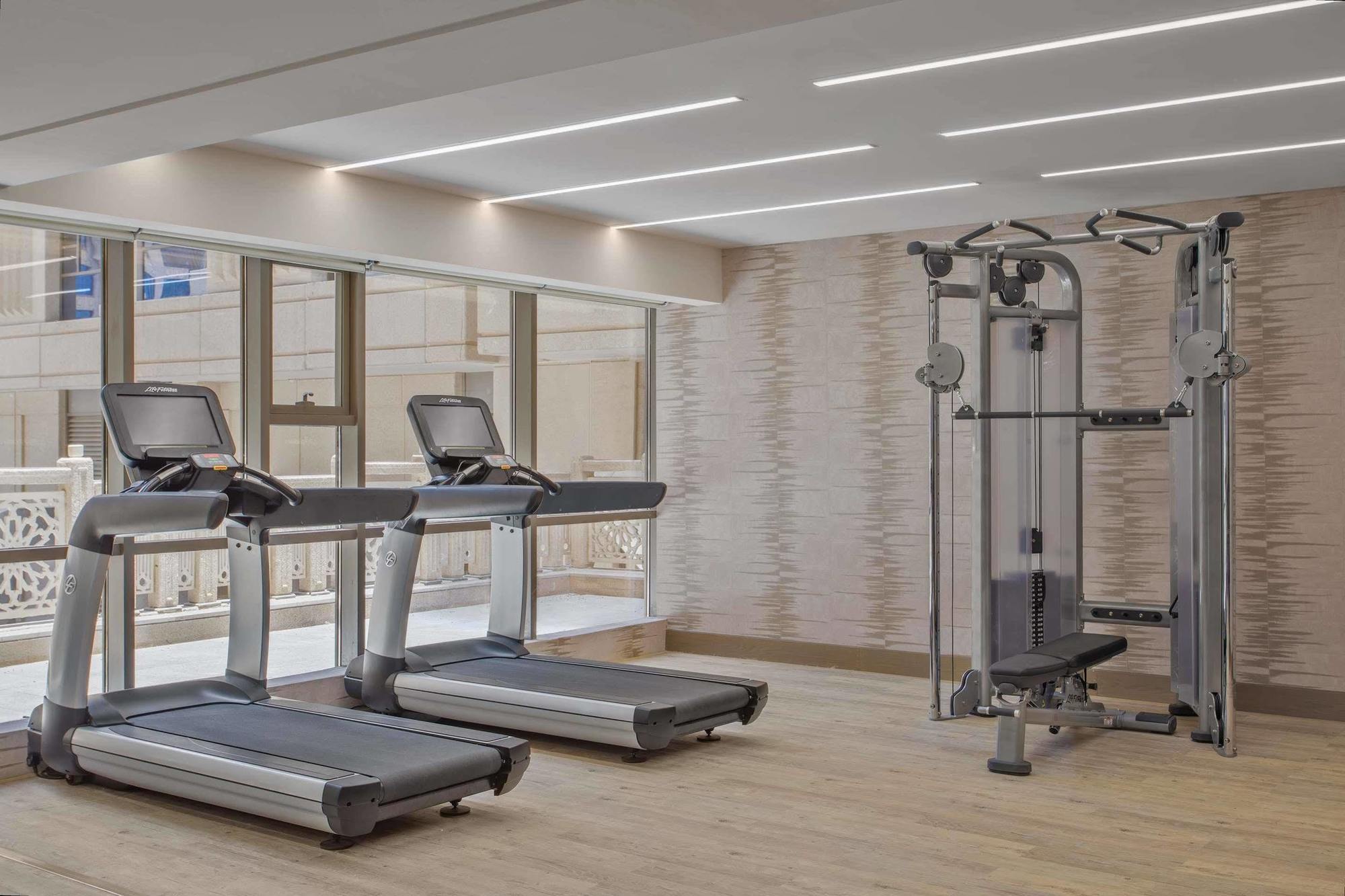 Hotel Jabal Omar Hyatt Regency Makkah La La Mecca Esterno foto The photo shows a modern gym area featuring two treadmills positioned side by side. Next to them is a multi-functional gym machine designed for strength training, which includes various attachments for different exercises. The gym has a bright, airy 